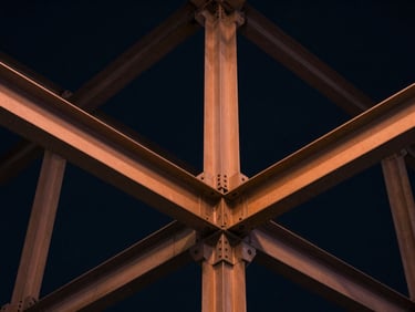 Extreme close-up of structured steel beams forming a perfect geometric grid, dramatic high-contrast lighting, deep navy ambient tones, 35mm lens.