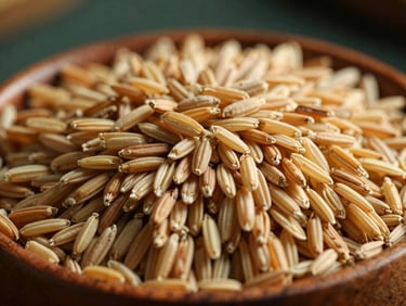 Close-up of golden-hued heritage rice grains resting in a hand-carved wooden bowl, soft natural light