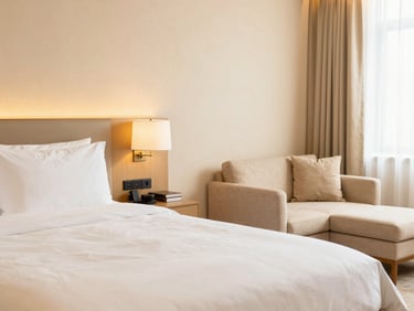 Elegant hotel suite with a separate seating area, refined soft gold accents, bright warm lighting, pristine linens, 35mm lens