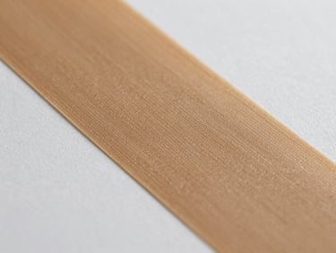 Macro shot of a specialty adhesive film print peeling from a liner, surface texture and ink adhesion visible in raking daylight, clean edge detail