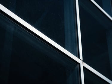 Macro close-up of dark architectural glass refracting cool light, sharp white lines, deep navy tones, cinematic 35mm photography