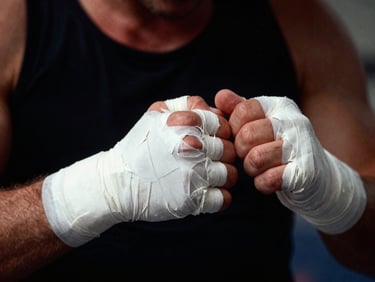Close-up of tightly wrapped hands in white tape, dark background with dramatic shadows, grit texture, 35mm film
