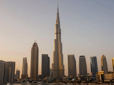 Wide environmental shot of Dubai skyline at golden hour, towering modern architecture reflecting warm light, clean composition with generous sky.