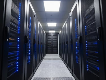 Wide overhead shot of a server rack room corridor, electric-blue LED indicator strips running along black rack units, cool white fluorescent ceiling lights casting sharp shadows on brushed steel surfaces, architectural symmetry with deep perspective depth
