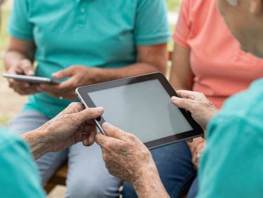 Close up of hands guiding a senior citizen on a tablet device during a digital workshop, warm natural light