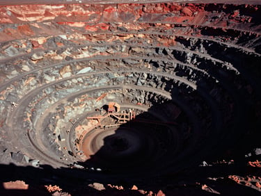 Dramatic high-altitude environmental shot of a massive desert copper mine, high-contrast chiaroscuro lighting, deep shadows, 35mm film grain