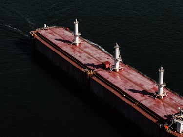 High-altitude architectural view of a massive deepwater cargo terminal, sharp directional light, stark black water, dramatic shadows