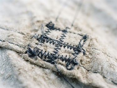 Extreme close-up of weathered white dacron sail cloth, detailed stitching and salt-crusted texture, soft coastal daylight, shallow depth of field