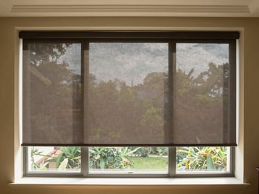 A premium sunlit balcony with durable external roller blinds rolled down, creating a cool shaded sanctuary.