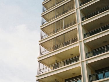 High-tensile invisible grills blending into the bright sky on a high-rise residential balcony, 35mm