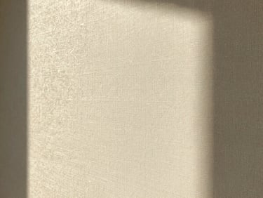 Close-up of textured champagne-toned designer wallpaper catching warm side light, rich paper fibers, 35mm