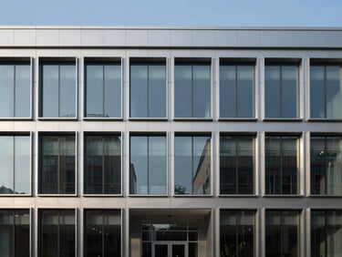 Straight-on architectural shot of a modern commercial office facade with clean steel and glass lines under crisp morning light