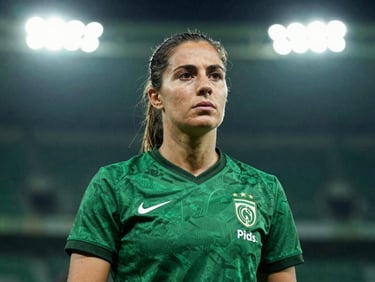 Candid portrait of a female football analyst looking thoughtfully off-camera, dramatic lighting, subtle green background, professional sports editorial style.