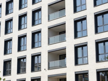 Clean architectural exterior of a modern multi-family residential building, brickwork details, bright daylight