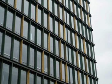 Detailed architectural crop of a modern corporate building facade, glass and steel reflecting overcast grey sky, Rotterdam, 35mm lens