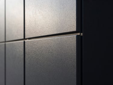 Détail architectural précis d'un angle de mur en béton banché lisse côtoyant une menuiserie en aluminium noir mat, lumière rasante du matin mettant en valeur la texture parfaite.