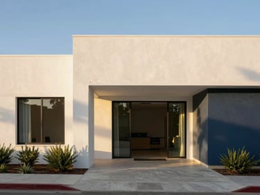 Bright modern architectural photography of a Mexicali house exterior, clean straight lines, warm golden hour sunlight reflecting off white concrete walls, olive green landscaping accents, 35mm lens