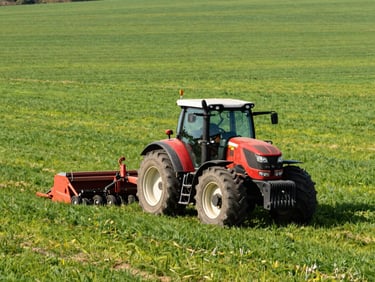 An agricultural tractor operating in a vibrant green field in Teramo province, bright natural daylight, realistic framing.