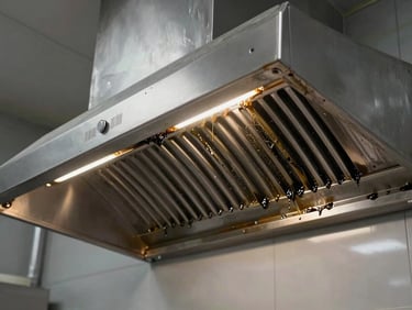 Industrial kitchen hood shining after heavy-duty grease cleaning, stainless steel surfaces reflecting bright utility lighting.