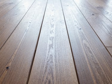 Close-up of perfectly aligned hardwood planks under natural light, showcasing grain and texture, low-angle, rich wood tones.