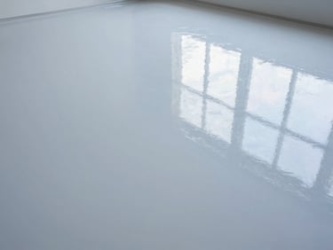 High-gloss epoxy garage floor with crisp reflections, wide-angle, bright overhead lighting, cool tones, emphasizing seamless finish.