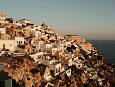 Sun-drenched cliffside village overlooking the Mediterranean sea, warm golden-hour natural light, rich taupe and sand tones, cinematic.