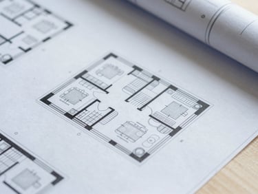 Overhead macro shot of architectural floor plans and structural drawings on a clean studio table, sharp focus, cool daylight.