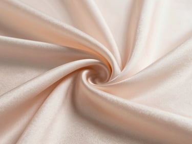 Close-up of luxurious silk fabric weave in blush and ivory, folded softly to reveal texture, bright north-facing daylight, shallow depth of field