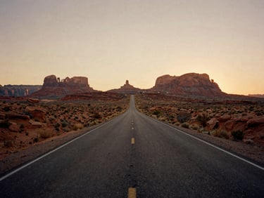 Wide panoramic empty asphalt road stretching towards red rock mesas under a warm golden sunset, dusty low-contrast 35mm film look