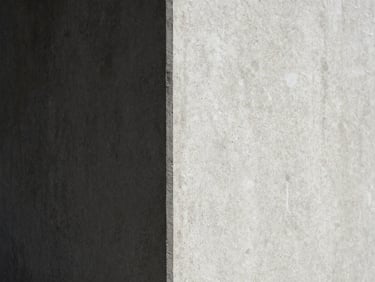 Minimalist close-up of a concrete corner, sharp diagonal shadow dividing the frame, high-contrast natural daylight, editorial texture.