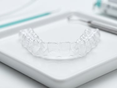 Macro photograph of a clear dental aligner showing high material clarity on a clean white clinical surface, bright high-key studio lighting, medical teal accents, shallow depth of field.