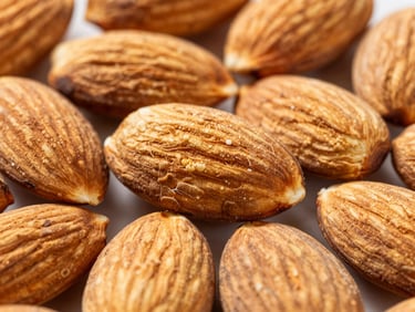 Macro shot of raw, shelled almonds clustered together, bright natural daylight highlighting textures.
