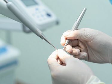 Close-up of a dentist's gloved hands carefully performing a tooth extraction, sterile instruments visible, bright clinical lighting.