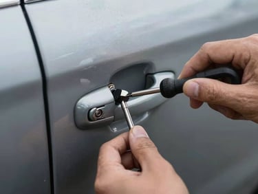 Tight shot of a locksmith tool inserted into a car door lock mechanism, vehicle door panel visible, harsh direct light, hands in focus, documentary style