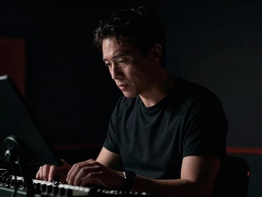 Portrait of a musician in a studio setting, dramatic low-key lighting, focused on their intense expression and instrument, cinematic film photography, deep blacks, subtle red accent, professional equipment visible.