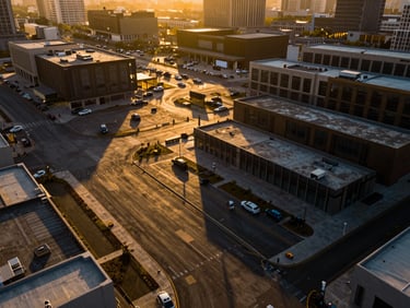 Crisp high-contrast architectural drone shot of a cleared urban commercial plot, golden hour shadows, rich gold and dark tones, wide-angle lens.