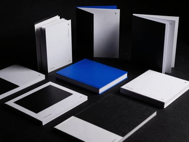 Dramatic studio shot of physical brand books and stationery, stark high-contrast lighting, 35mm film.