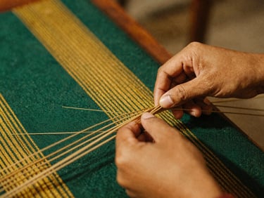 Close up of hands weaving traditional Indonesian textile, rich textures, warm ambient lighting