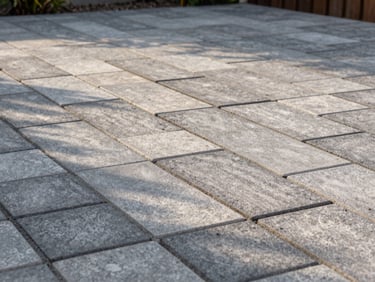 Freshly laid paving stones on a new garden terrace, mortar joints still clean, afternoon light raking across the surface texture, no people