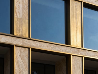 Bespoke architectural facade detailing with brushed gold accents and natural stone, clean daylight, high contrast