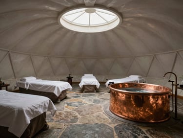 An Ayurvedic wellness dome interior with dedicated meditation space, raw stone floors, and a copper soaking tub under a skylight