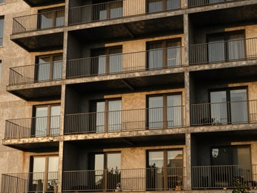 Architectural exterior of a modern multi-family apartment building with raw steel balconies, golden-hour light, 35mm