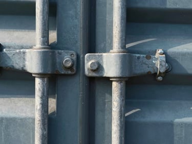 Macro close-up of heavy industrial steel bolt seals on a shipping container door, sharp focus, cool steel tones.
