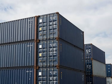 High-contrast wide environmental shot of stacked shipping containers at ICD Tuglakabad under an overcast industrial sky, 35mm.