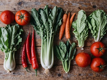 Vibrant overhead flat-lay of seasonal organic vegetables arranged beautifully on a rustic wooden table, tactile matte texture.