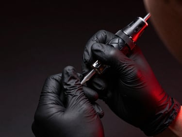 Macro shot of a tattoo artist's hands with black gloves meticulously preparing a needle cartridge, dramatic red side-lighting, dark background