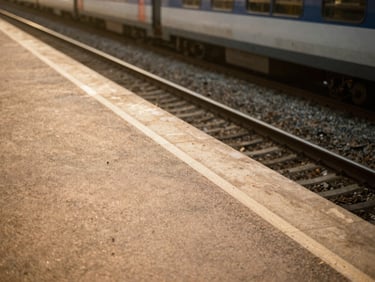 An empty train platform along a regional line in southern France, soft golden hour light, warm sand tones.
