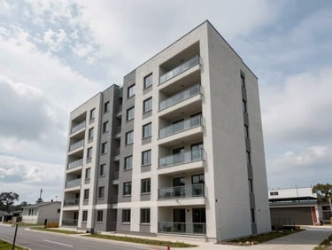 Wide exterior of a newly completed residential building with visible balconies, overcast natural daylight, surrounding road and open sky providing location context, no people