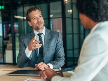 Professional businessman in a grey suit leading an executive interview in a modern office.