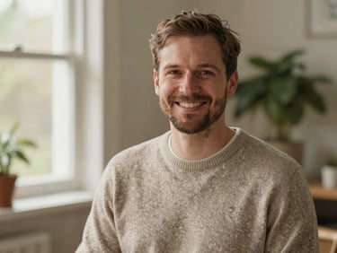 Warm portrait of a friendly Dutch male nurse in his 30s, wearing a casual sweater, smiling warmly, soft natural outdoor light in a garden setting.